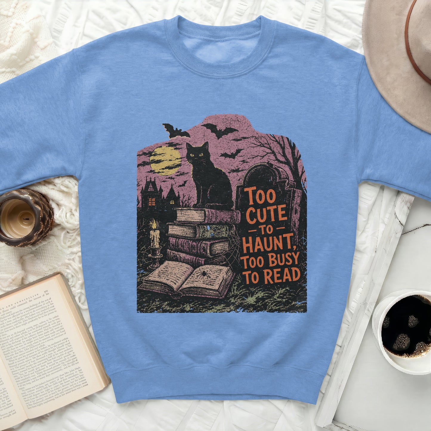 Black cat on books with "Too Cute To Haunt, Too Busy To Read" text.