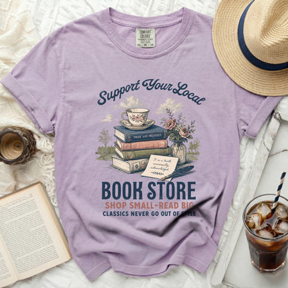 Purple t-shirt with "Support Your Local Book Store" graphic and books.