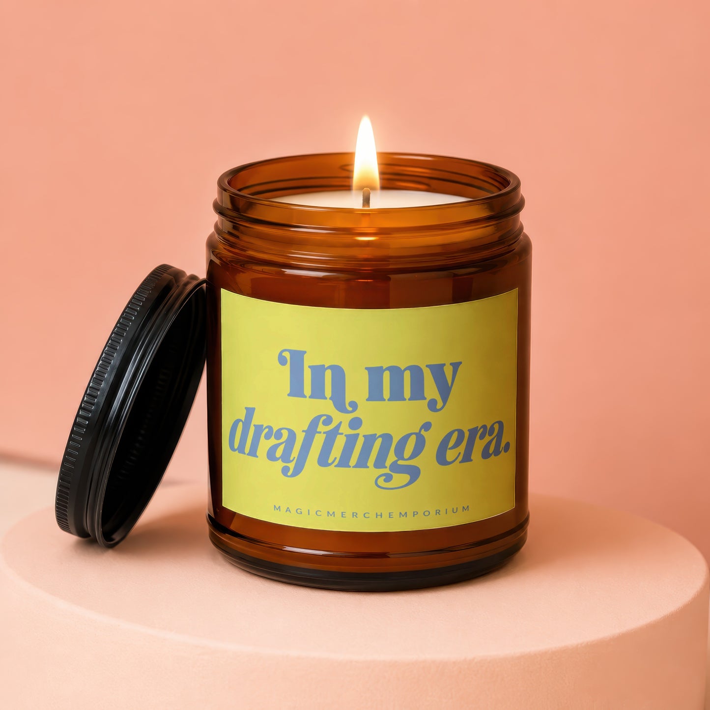 Amber jar candle lit with the words "In my drafting era.".