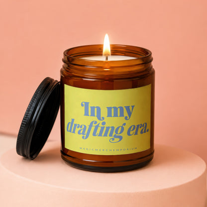 Amber jar candle lit with the words "In my drafting era.".