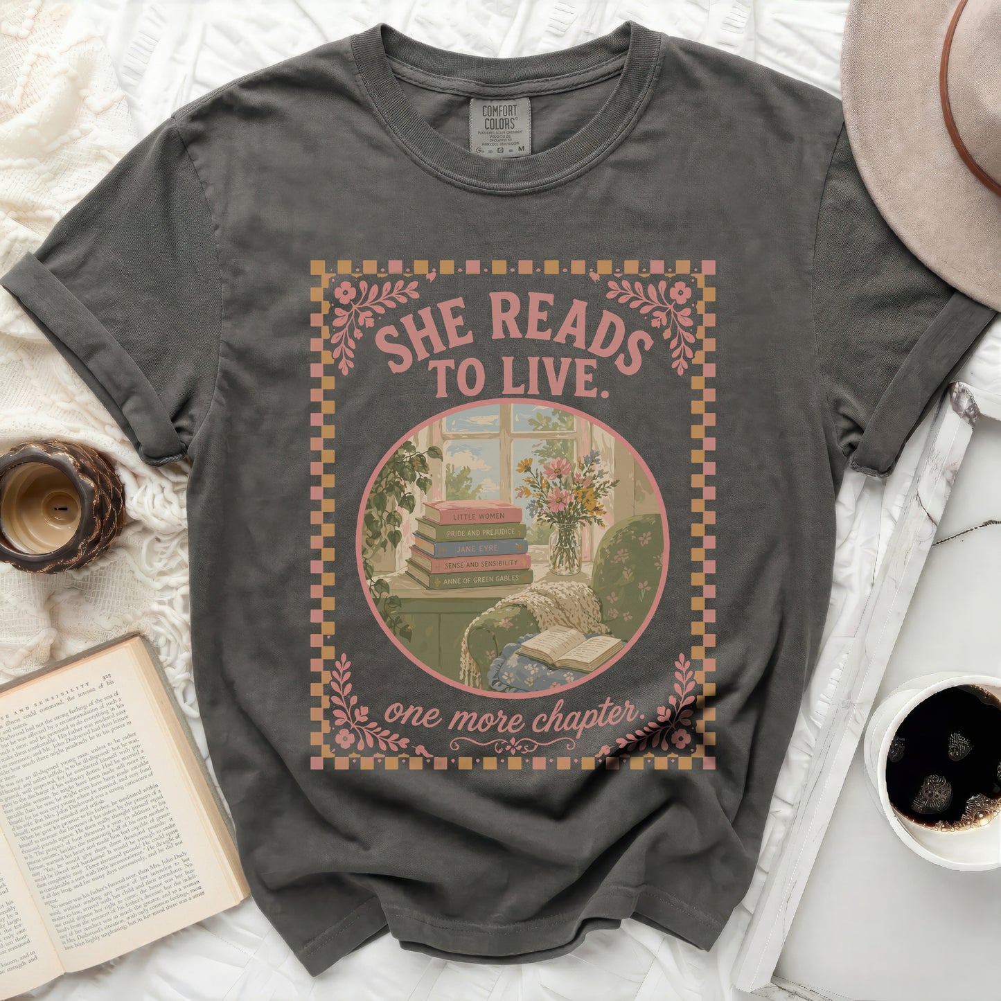 Dark grey t-shirt with "She Reads to Live. One More Chapter." text and books.