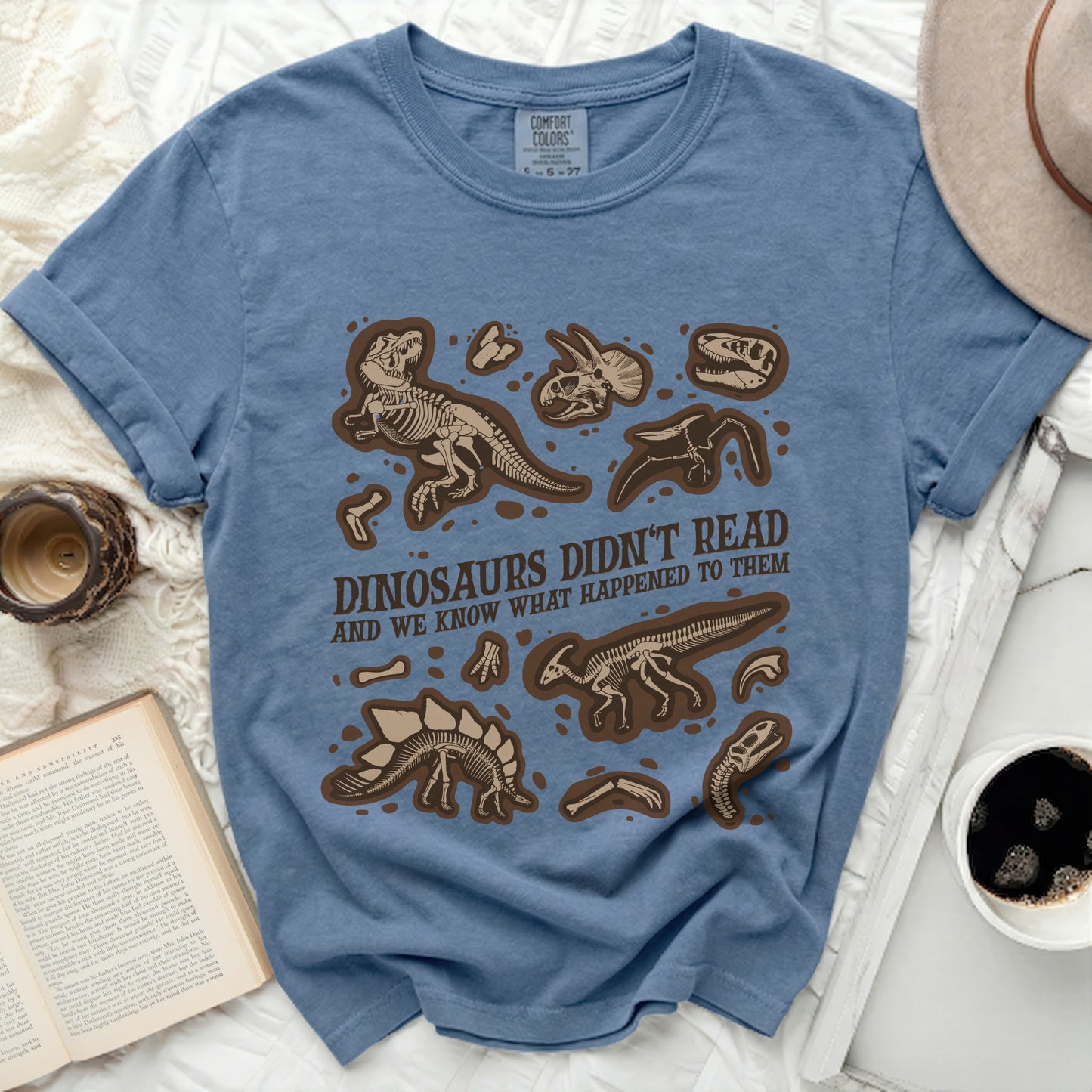 Blue t-shirt with dinosaur skeletons and text "DINOSAURS DIDN'T READ AND WE KNOW WHAT HAPPENED TO THEM".