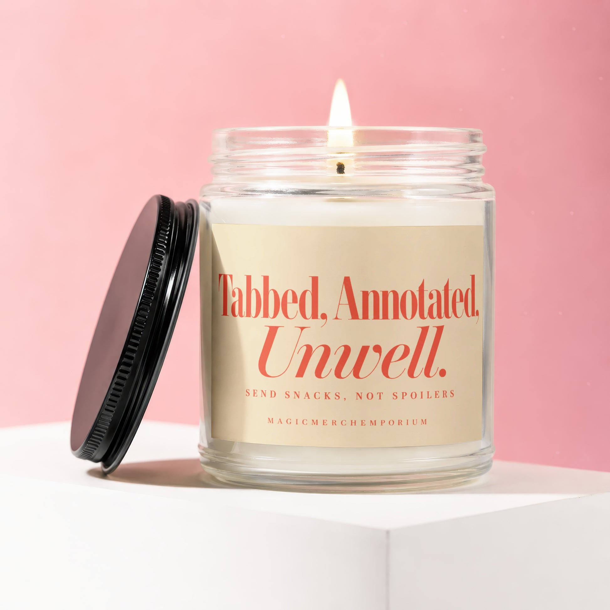 Candle with "Tabbed, Annotated, Unwell. Send Snacks, Not Spoilers" text and lid off.