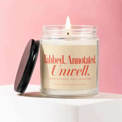 Candle with "Tabbed, Annotated, Unwell. Send Snacks, Not Spoilers" text and lid off.