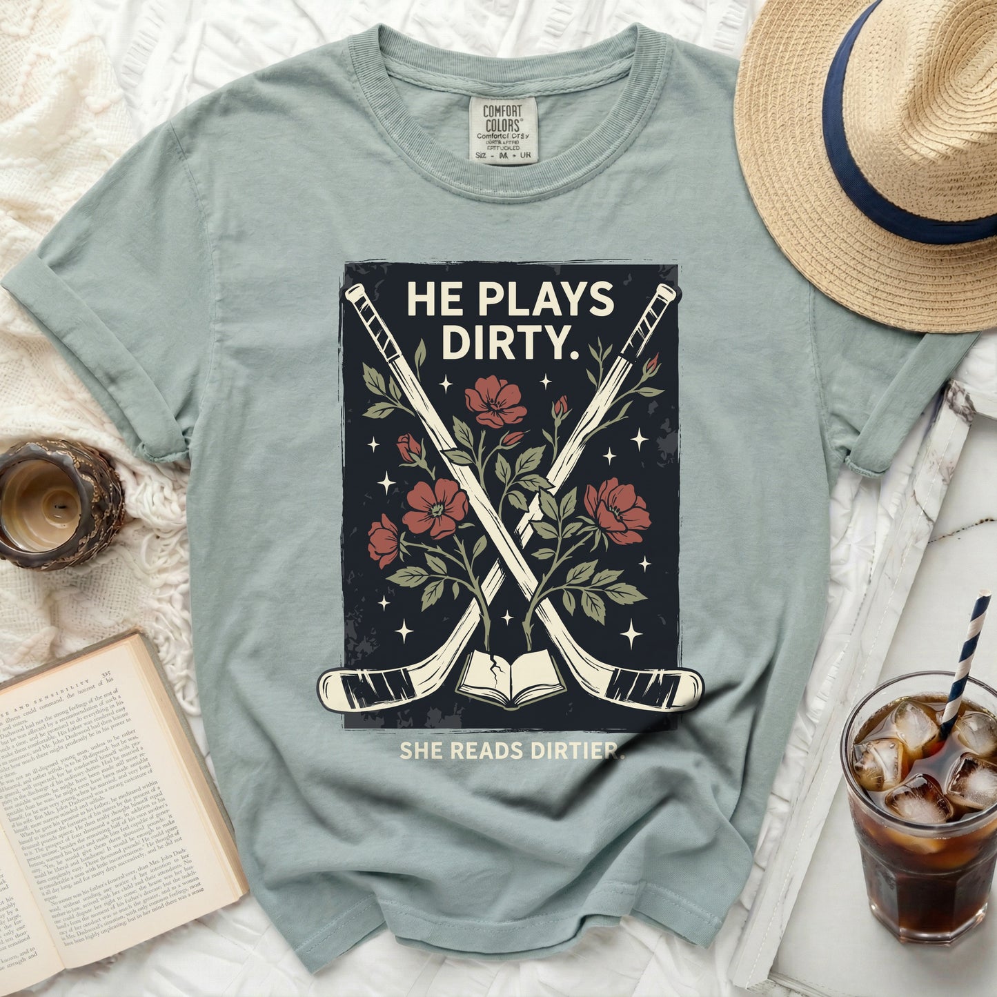T-shirt with hockey sticks, flowers, and book, reading "HE PLAYS DIRTY. SHE READS DIRTIER."