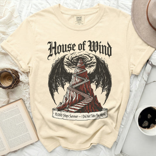 A cream t-shirt with a graphic of "House of Wind" and a winding staircase.