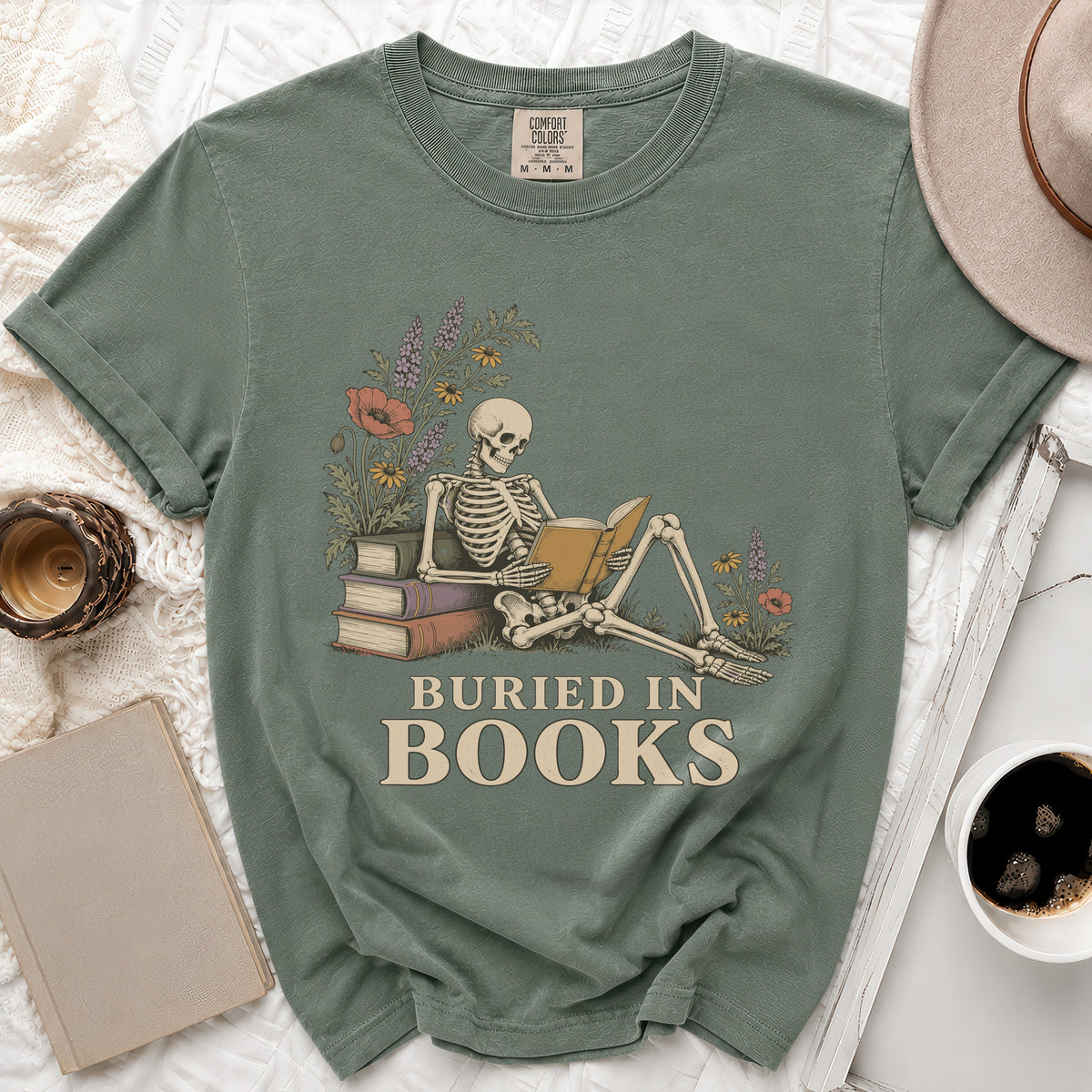 Skeleton reading a book with flowers and text "Buried in Books".
