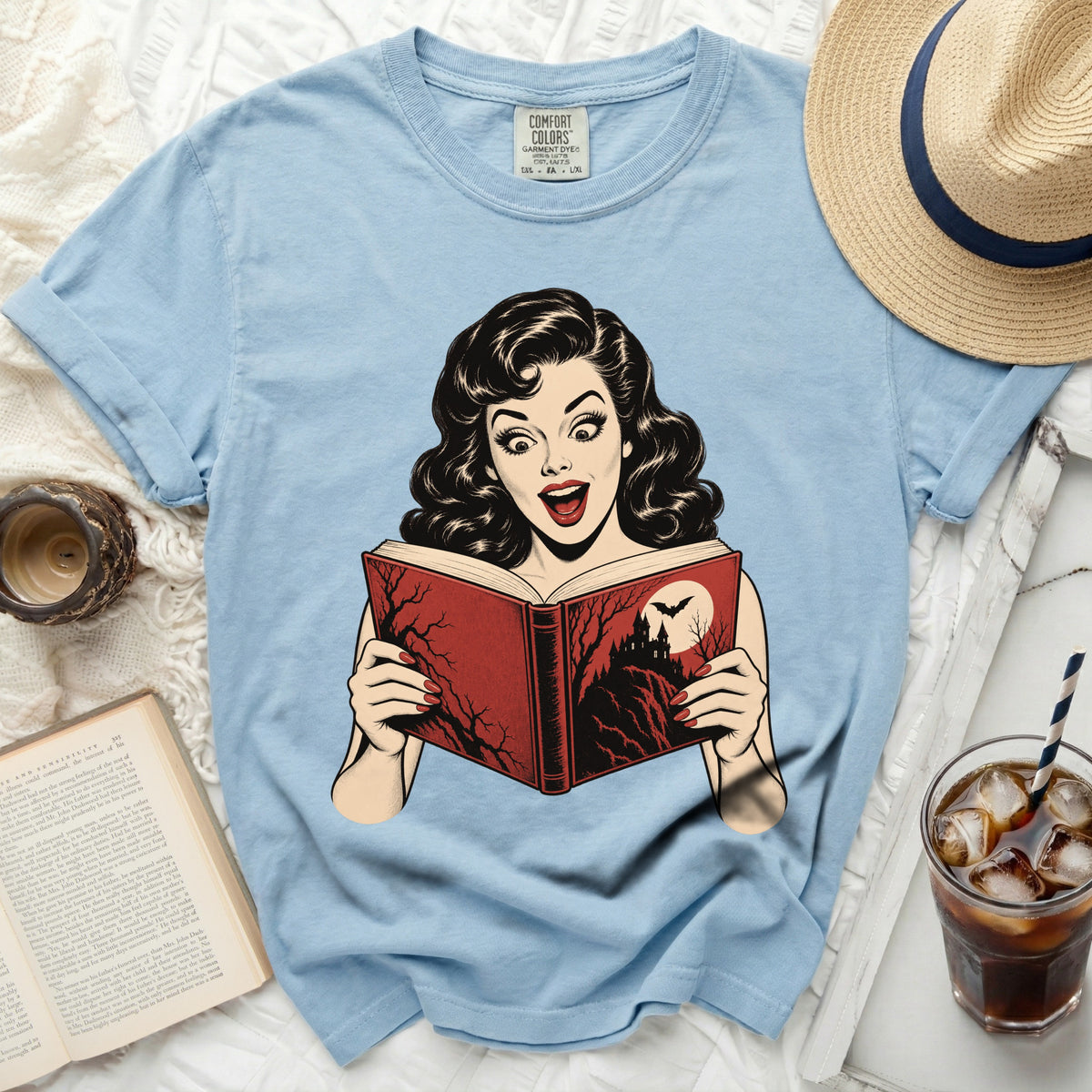 Light blue t-shirt with comic book style graphic of surprised woman reading a spooky book.