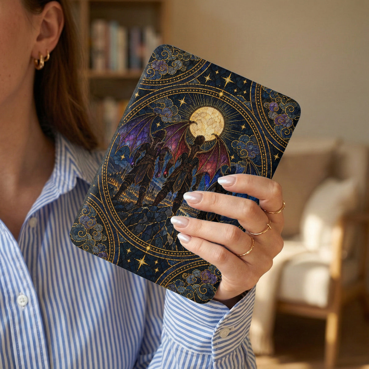 A person in a blue-striped shirt holds an e-reader featuring a stained glass-style nocturnal fantasy design.