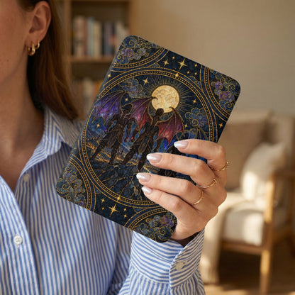 A person in a blue-striped shirt holds an e-reader featuring a stained glass-style nocturnal fantasy design.