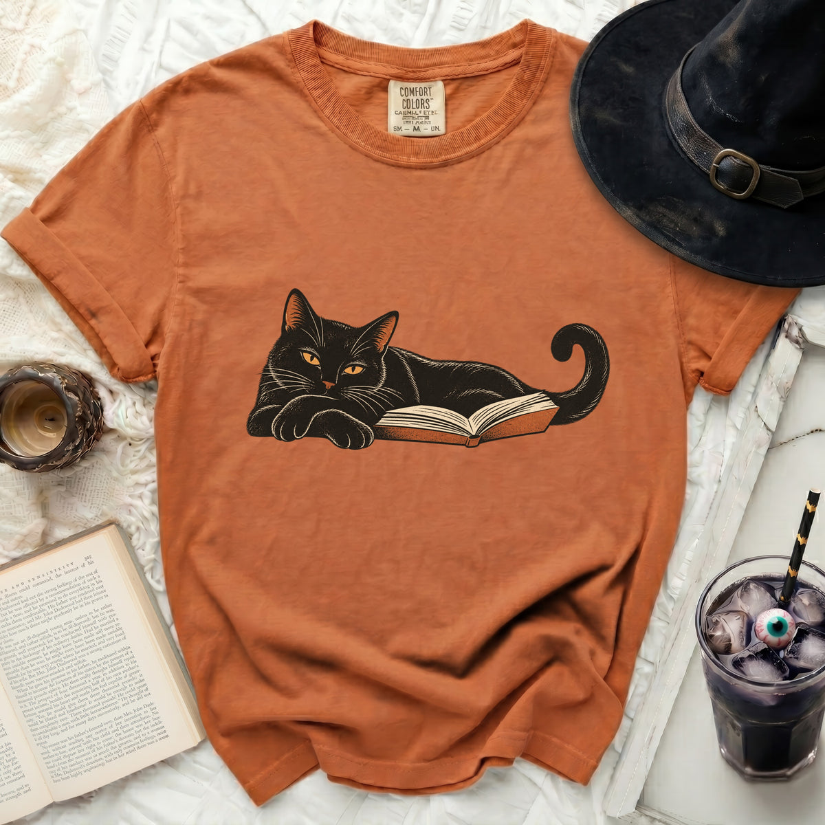 Orange t-shirt with a black cat resting on an open book graphic.