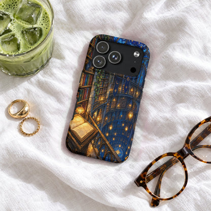 Black phone case with a magical library illustration, resting on a white fabric surface with glasses and iced matcha.