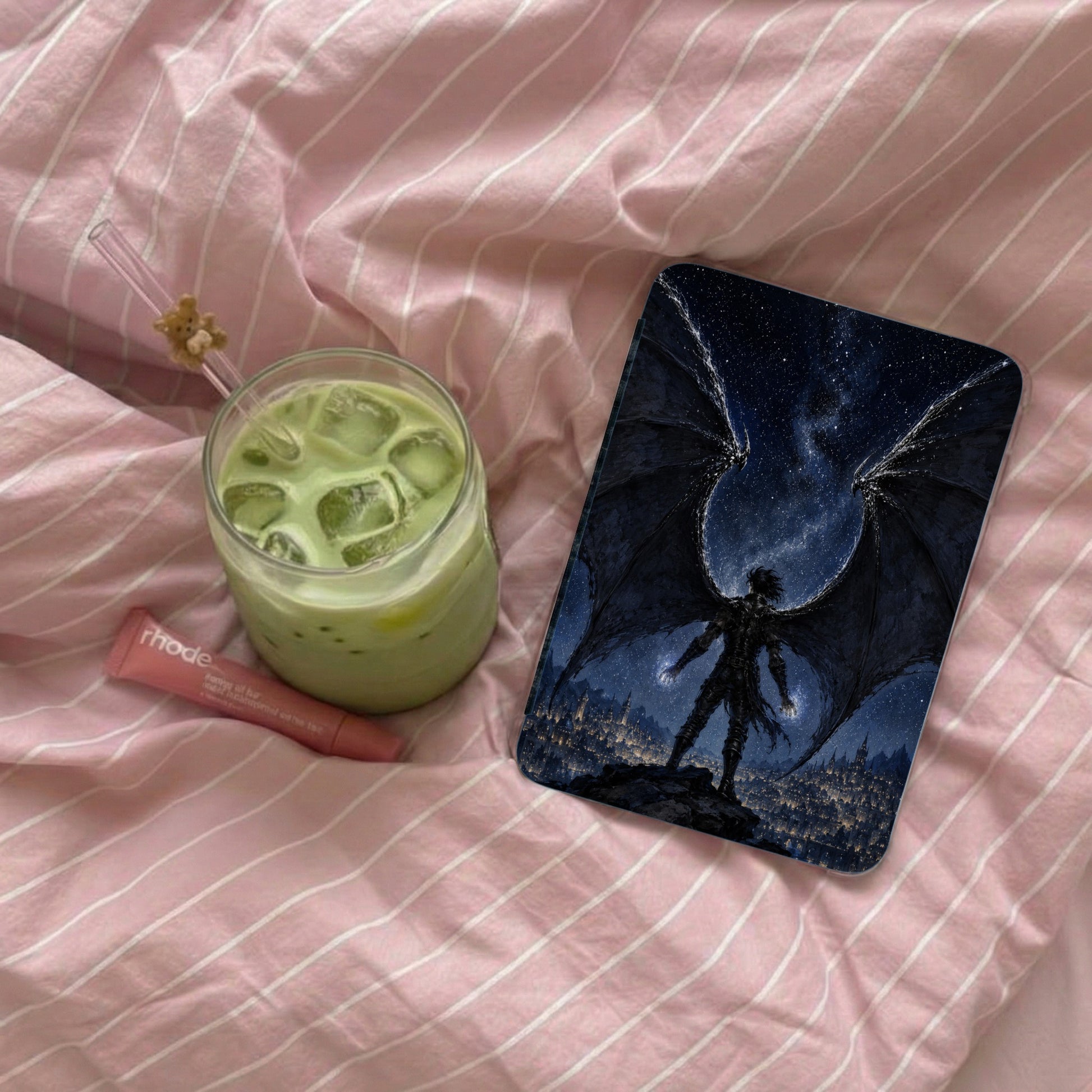 Matcha latte, lip balm, and phone case featuring a winged figure over a city skyline.