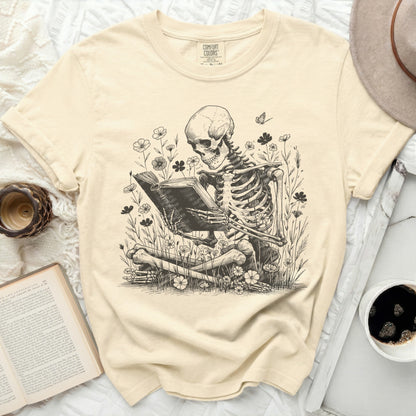 Skeleton reading a book among flowers and a butterfly.