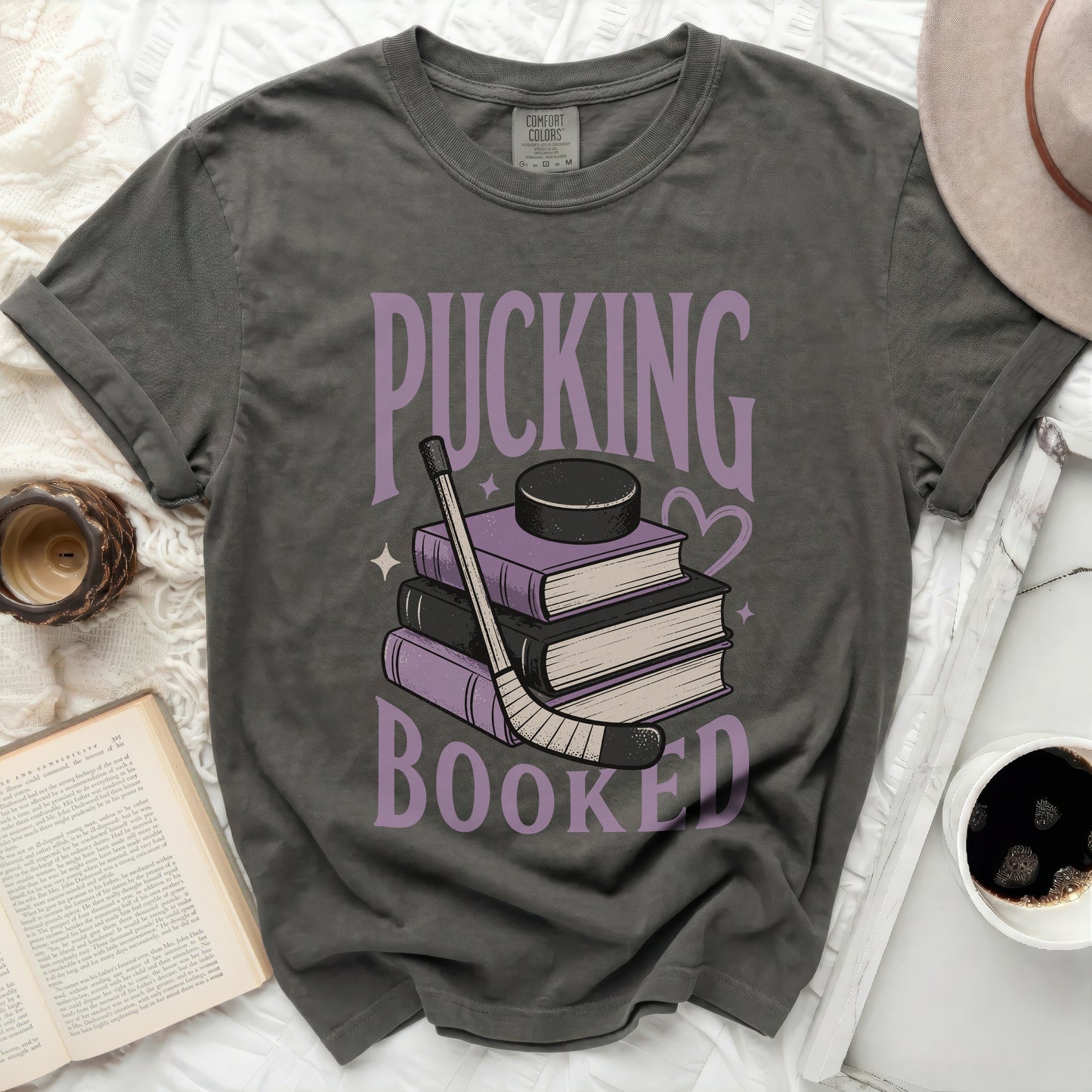 Dark gray t-shirt with "Pucking Booked" text and hockey puck on books.