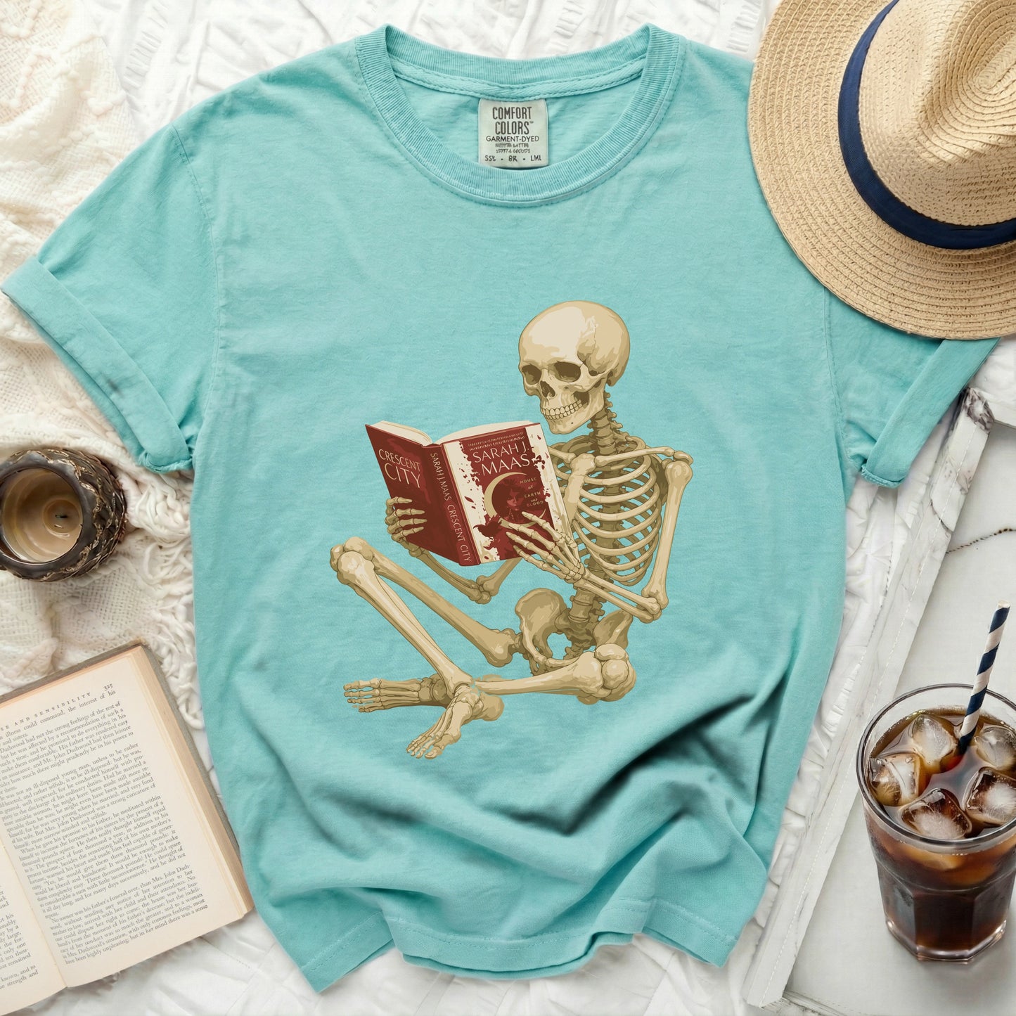 Skeleton reading a book titled "Crescent City" by Sarah J. Maas.