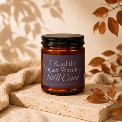 Amber jar candle with "I Read the Trigger Warnings. Still Cried." text on purple label.