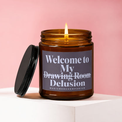 Amber candle with burning wick, lid beside it, labeled "Welcome to My Drawing Room Delusion."