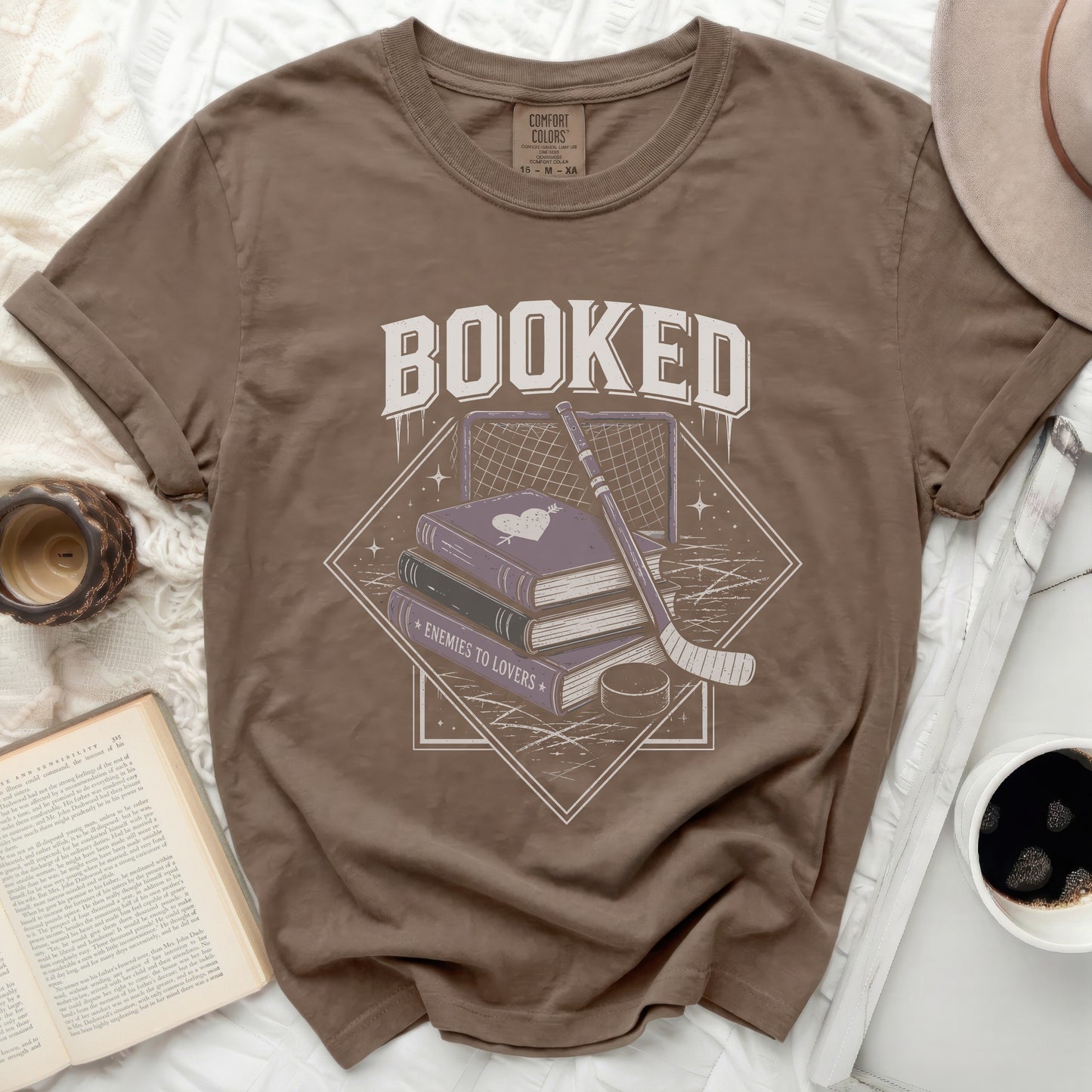 Brown t-shirt graphic with books, hockey puck, stick, and net.