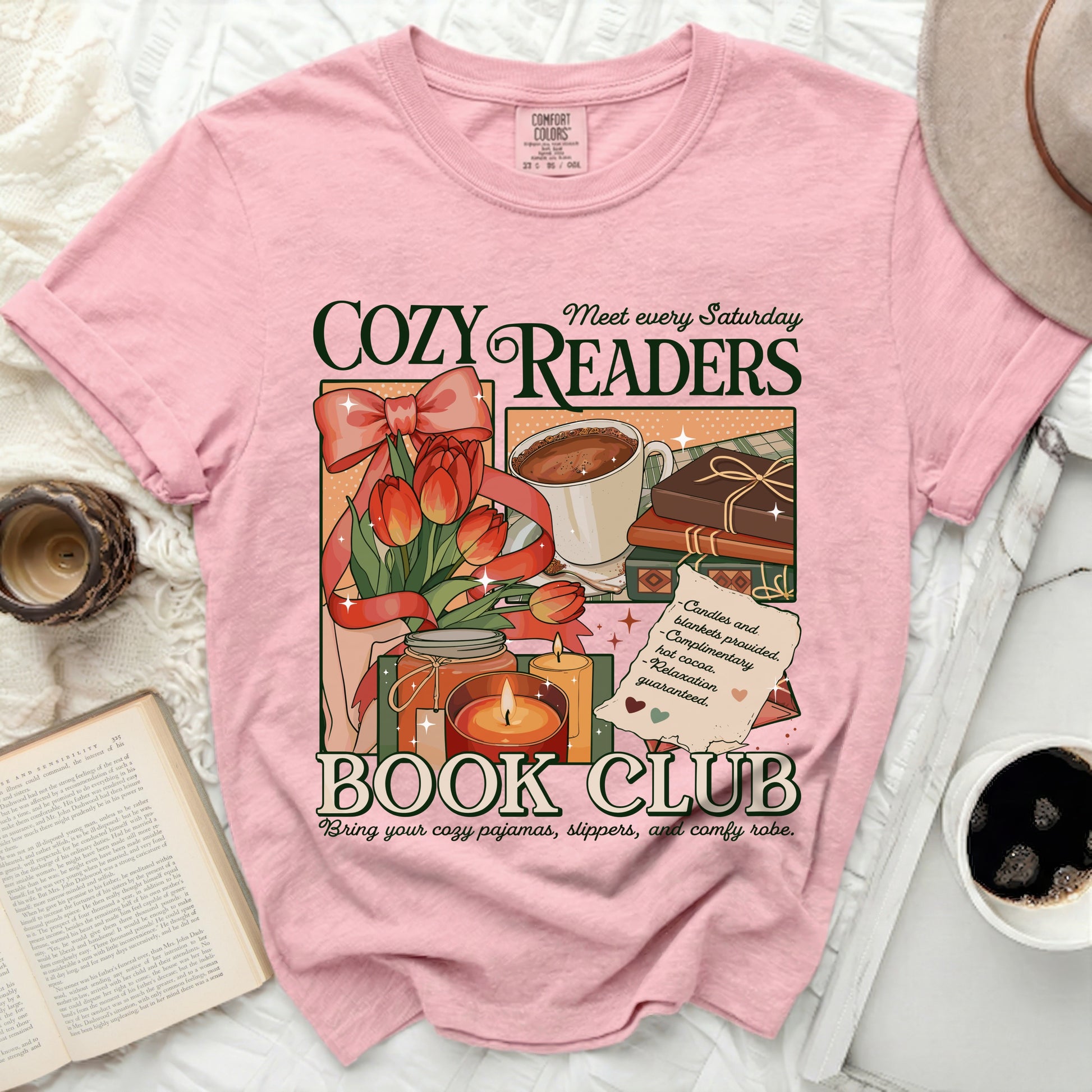 Pink t-shirt with "Cozy Readers Book Club" graphic featuring tulips, hot cocoa, books, and candles.
