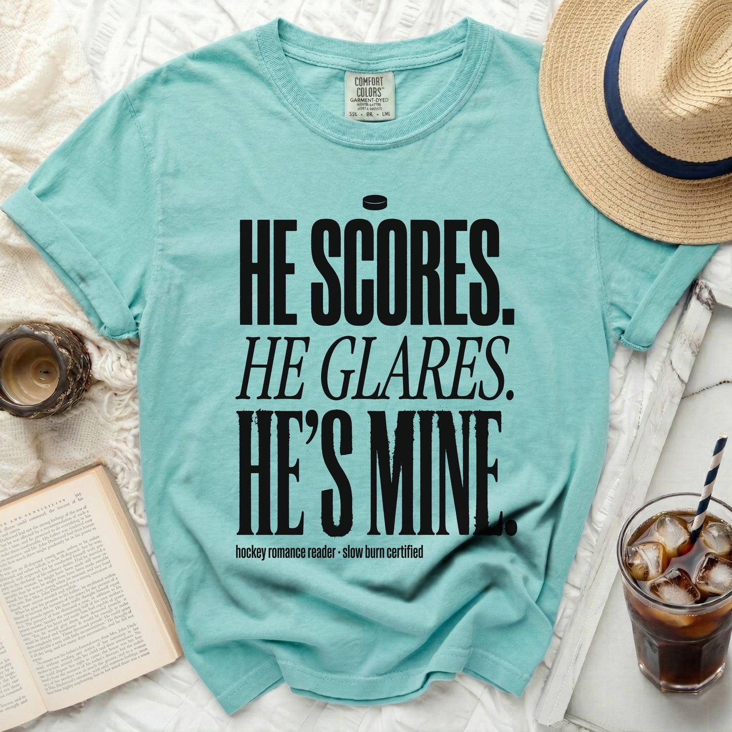 Teal t-shirt with bold black text "HE SCORES. HE GLARES. HE'S MINE."