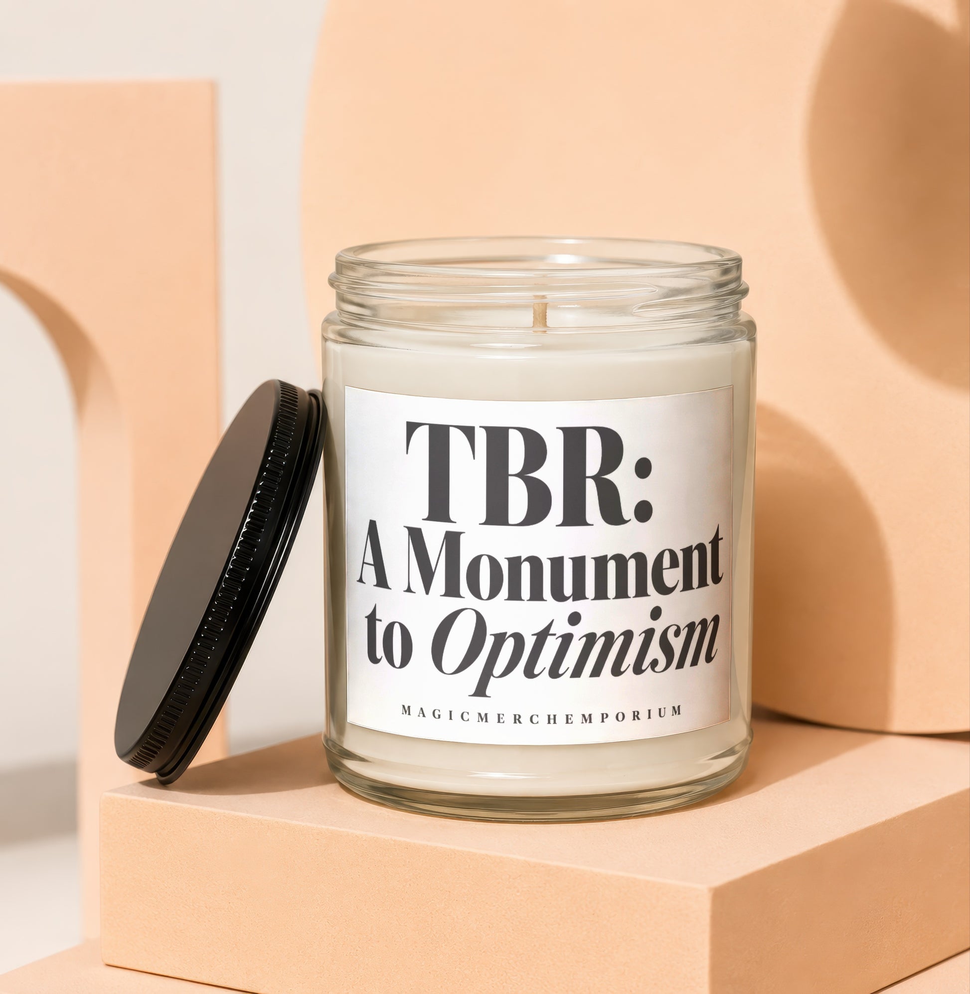 Glass candle with black lid, labeled "TBR: A Monument to Optimism".