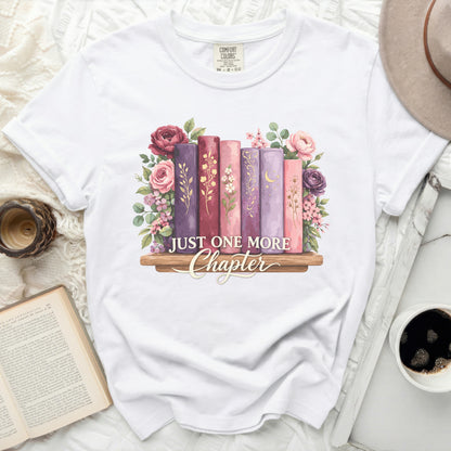 White t-shirt with "Just One More Chapter" graphic of books and flowers.