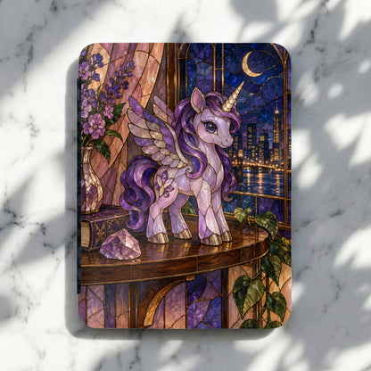 Stained glass unicorn with wings stands on a table by a city window at night.