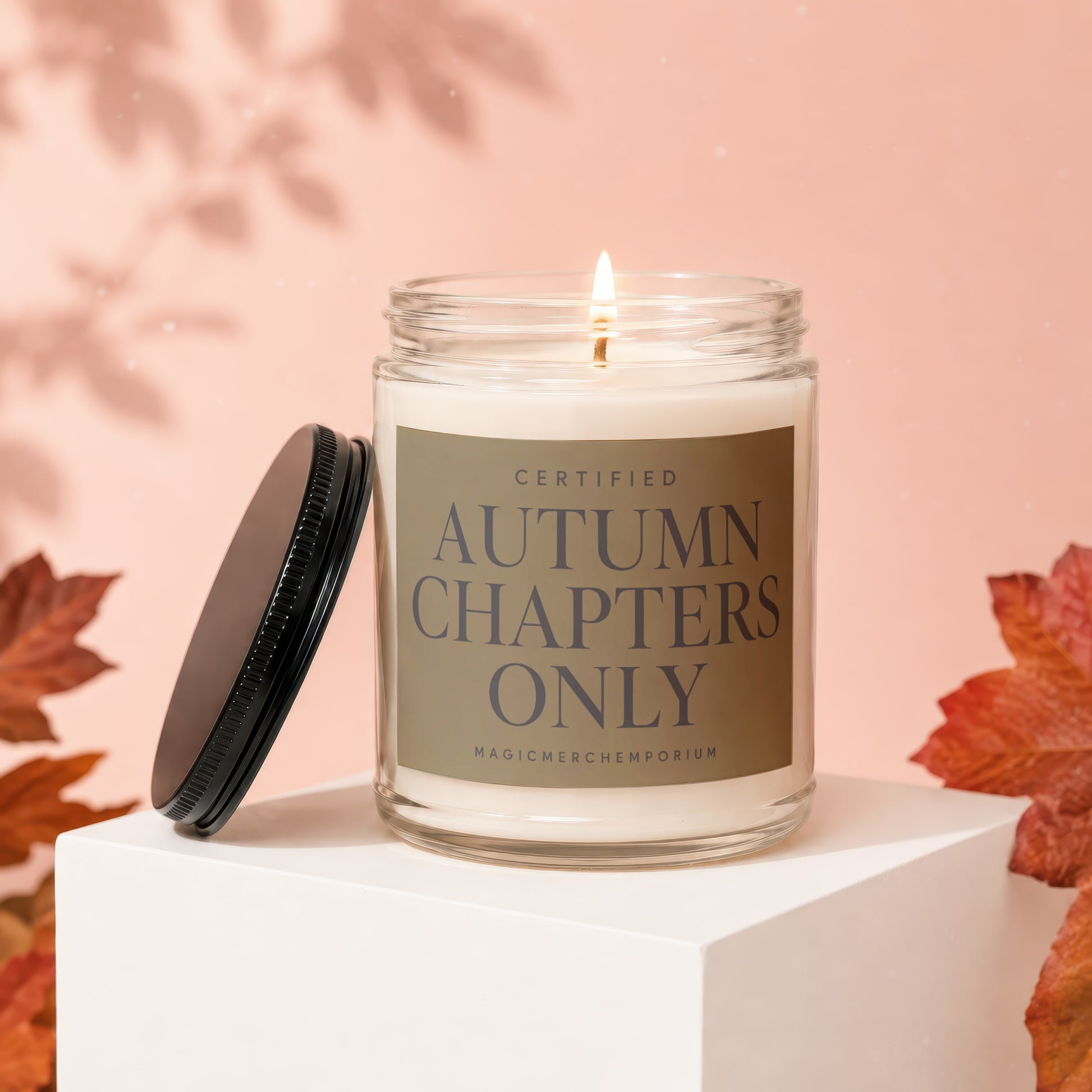 Candle with label reading "Certified Autumn Chapters Only" on a white cube.
