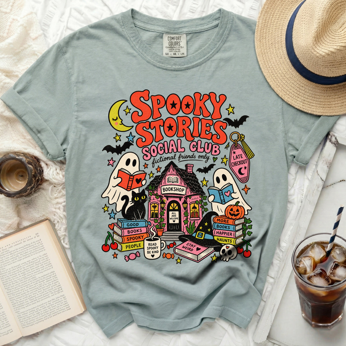 "Spooky Stories Social Club" t-shirt with ghosts, black cat, bookshop, and Halloween imagery.