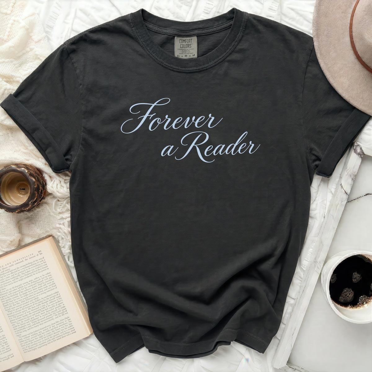 Dark t-shirt with "Forever a Reader" text, near an open book.