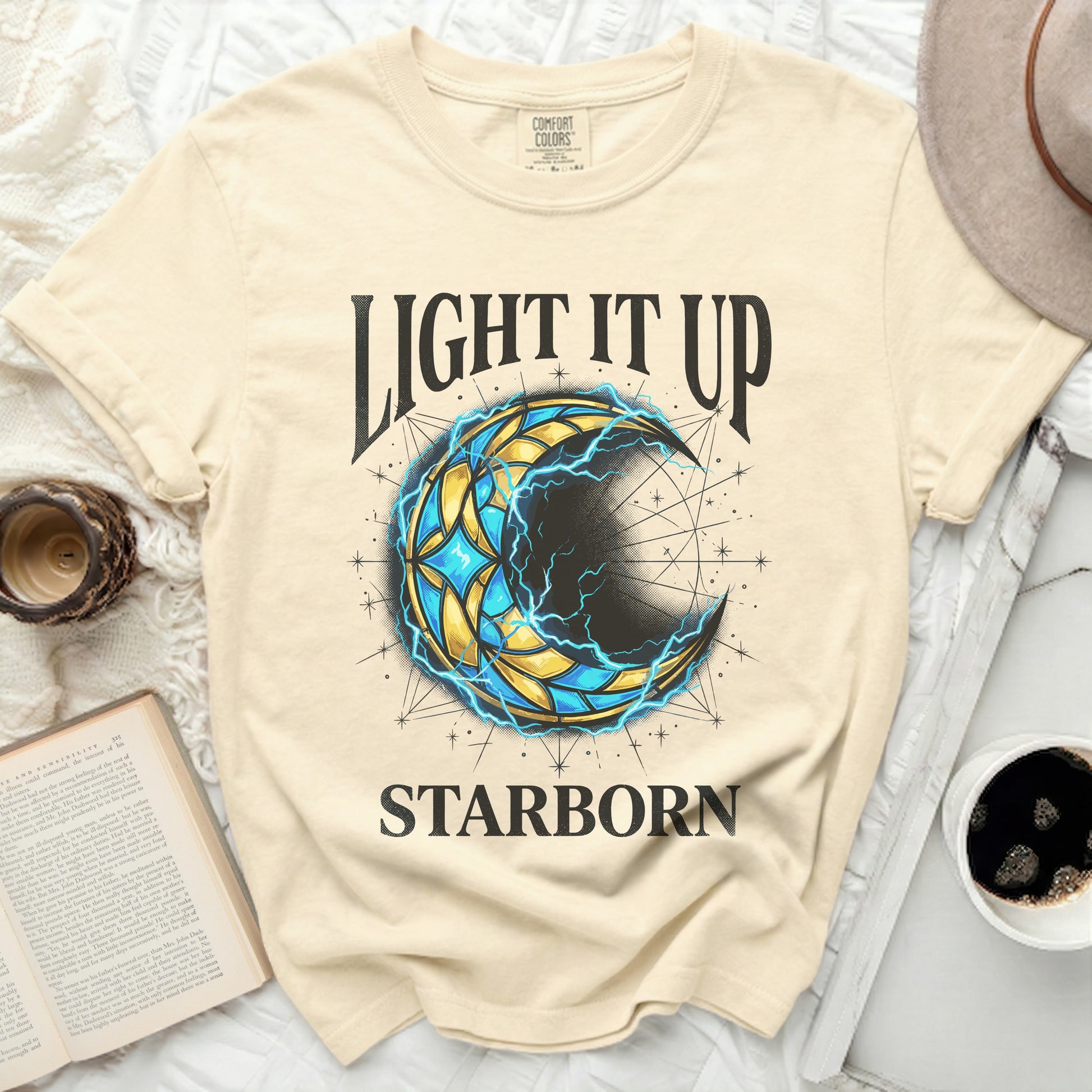 Cream t-shirt with "LIGHT IT UP STARBORN" and a crescent moon design.