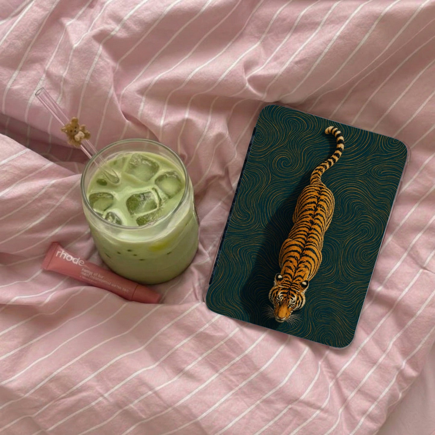 Tiger print phone case next to matcha drink and Rhode lip balm.