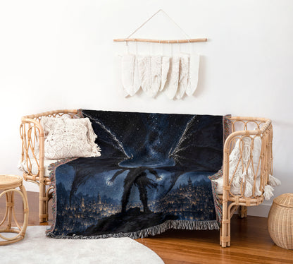 a cozy living room with a wicker bench and a woven chair, both adorned with a blue and black blanket that depicts a cityscape at night. The blanket has a starry sky and a silhouetted figure, creating a whimsical and dreamy atmosphere. The room is decorated with a hanging feather wall art piece and a woven basket, adding to the overall aesthetic of the space.