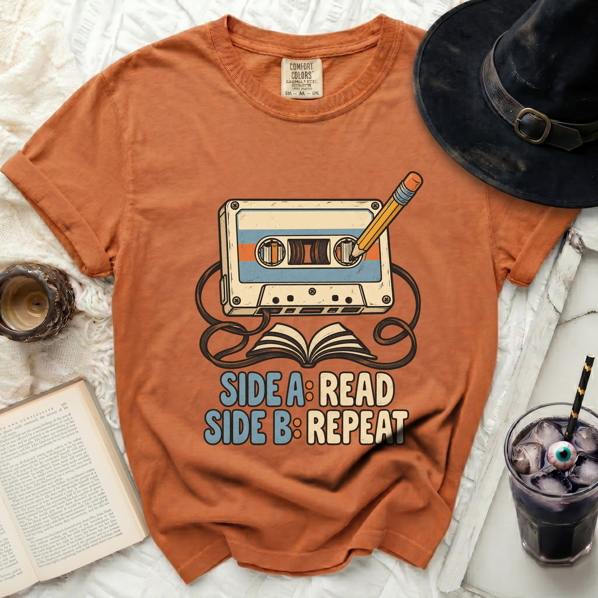 Orange t-shirt with cassette tape, pencil, book, and text "SIDE A: READ SIDE B: REPEAT".