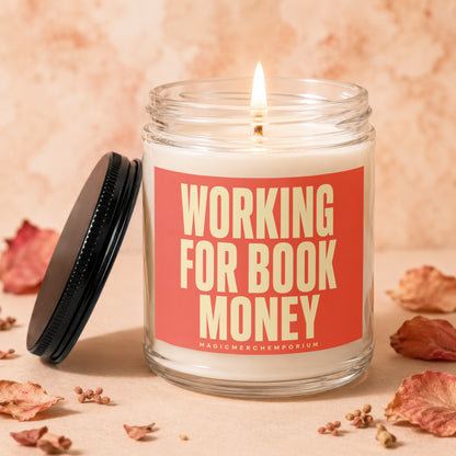Glass candle with lit wick and "Working for Book Money" text.