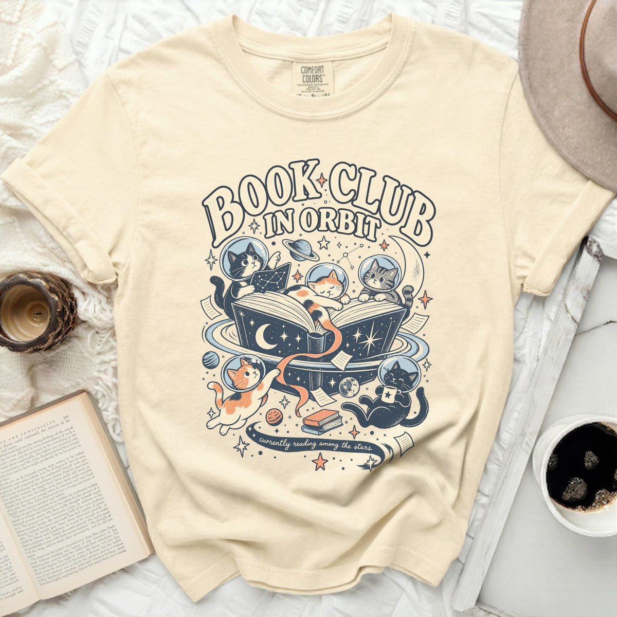 Cream t-shirt with "Book Club In Orbit" and cats in space reading.