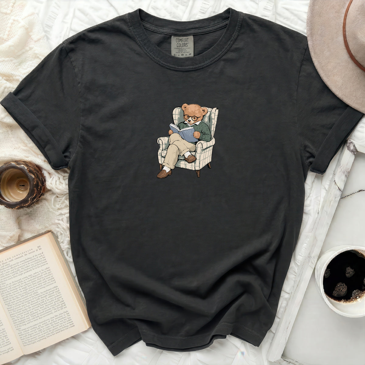 Dark grey t-shirt with a graphic of a bear in glasses reading in an armchair.