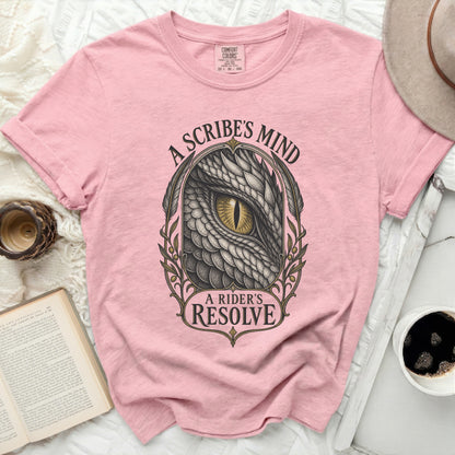Pink t-shirt featuring a graphic of a dragon eye with text reading A Scribe's Mind and A Rider's Resolve.