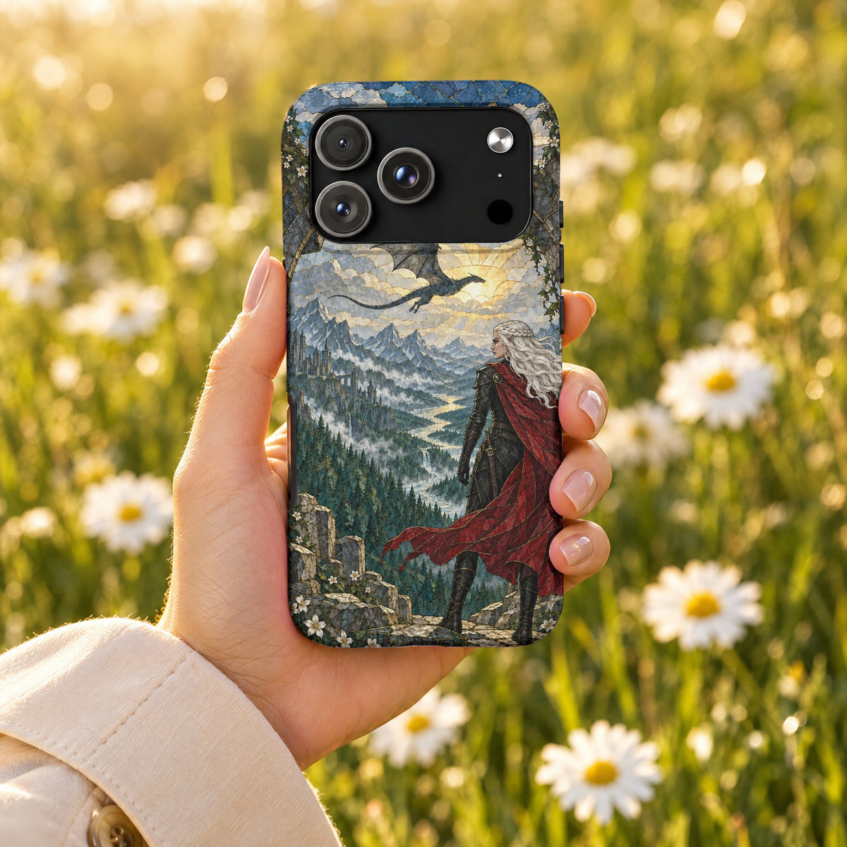 A hand holds a smartphone with a mosaic-style fantasy art phone case showing a queen and a flying dragon over mountains.