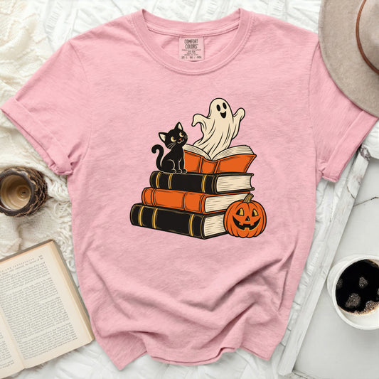 Pink Comfort Colors t-shirt with a Halloween graphic of a cat, ghost, and pumpkin on books.