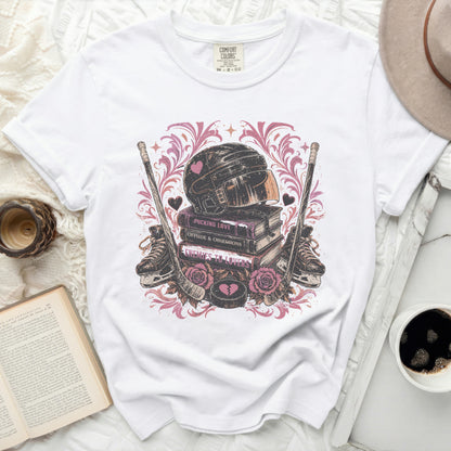 White t-shirt with hockey gear, books, and hearts graphic.
