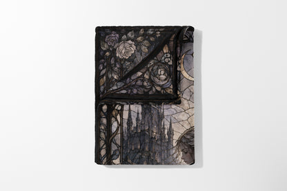 Folded blanket with stained glass design of roses, castle, and a woman.