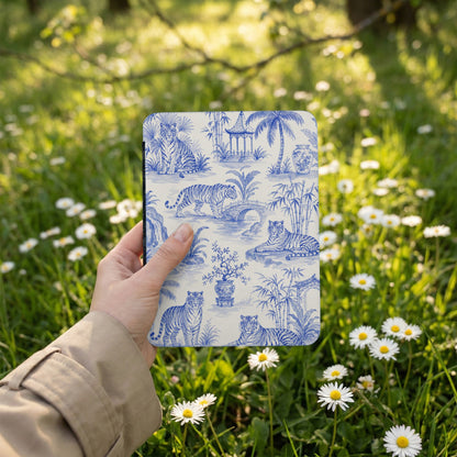Blue and white toile pattern with tigers, bamboo, and pagodas on a flat object held outdoors.