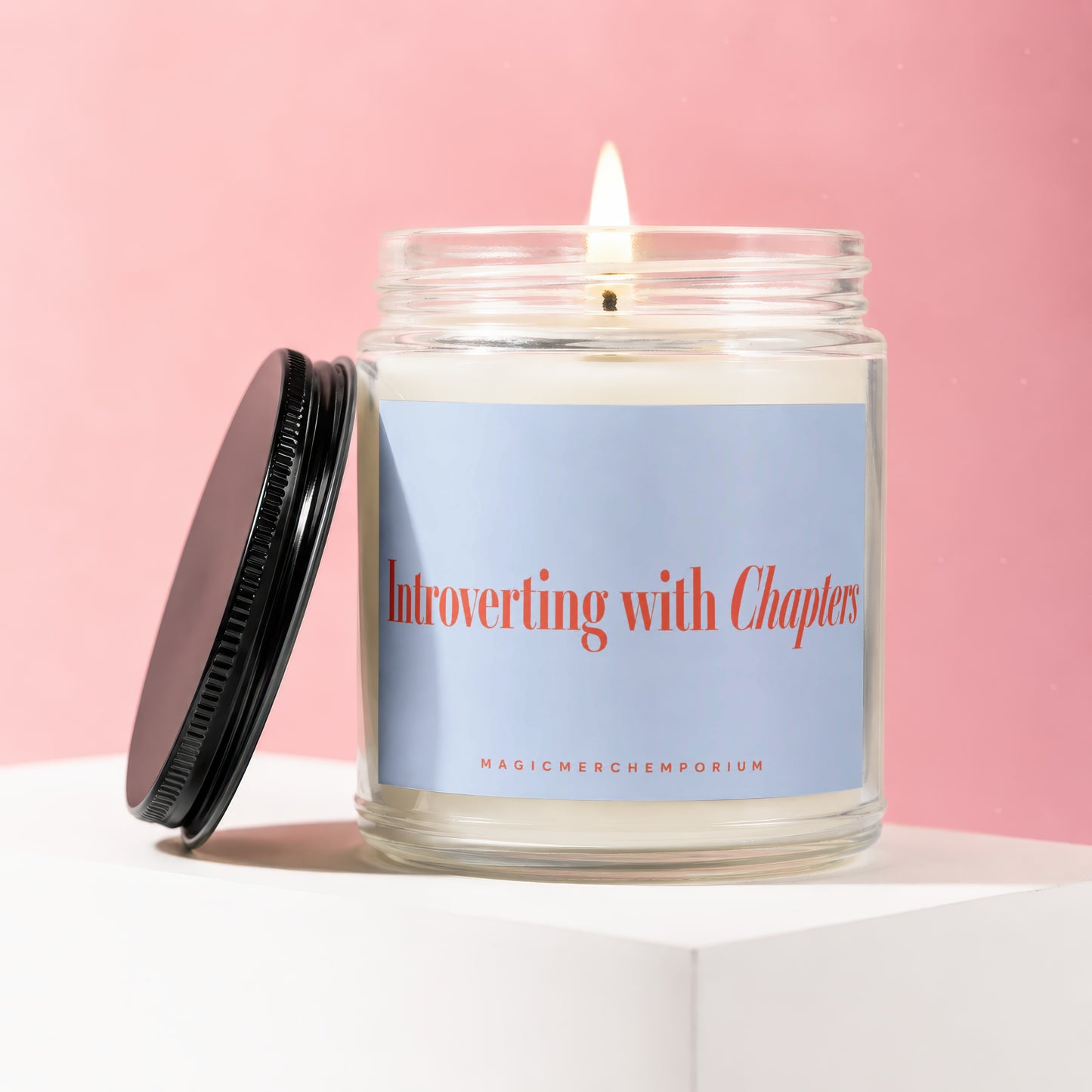 Jar candle with lit wick, "Introverting with Chapters" text on blue label.