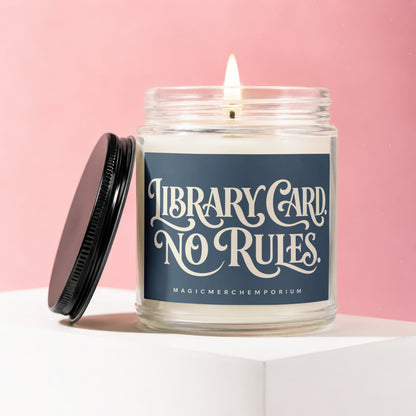 Glass candle with lit wick and black lid, reads "Library Card No Rules"