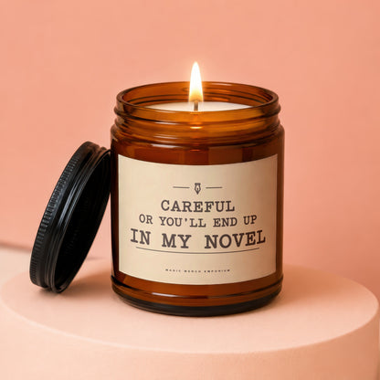 Amber jar candle with lit wick, lid off, reads "Careful Or You'll End Up In My Novel."