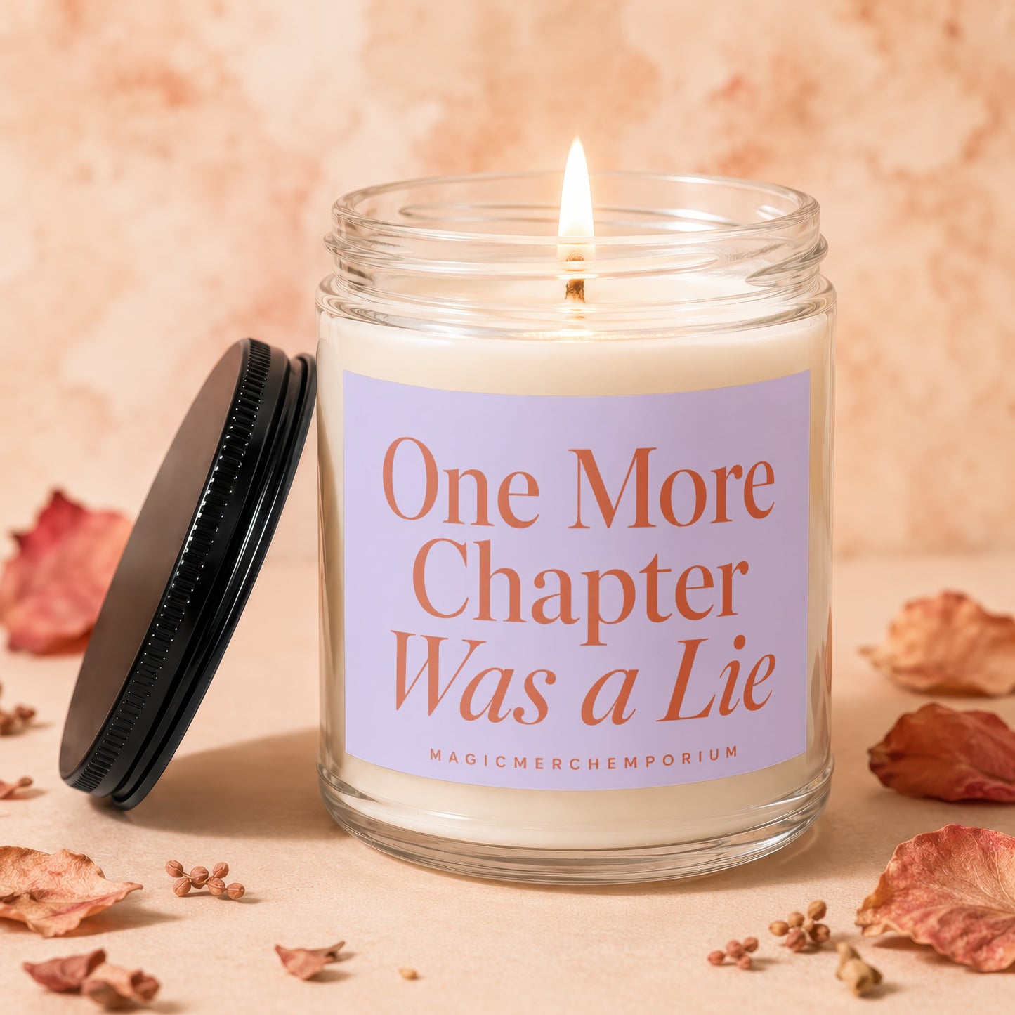 Lit candle in glass jar with a purple label that reads "One More Chapter Was a Lie".