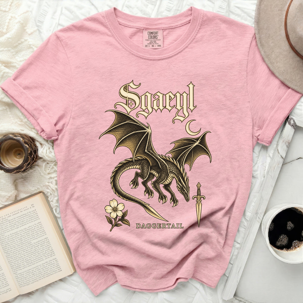 Pink t-shirt with a gold dragon, flower, sword, and text "Sgaeyl DAGGERTAIL".