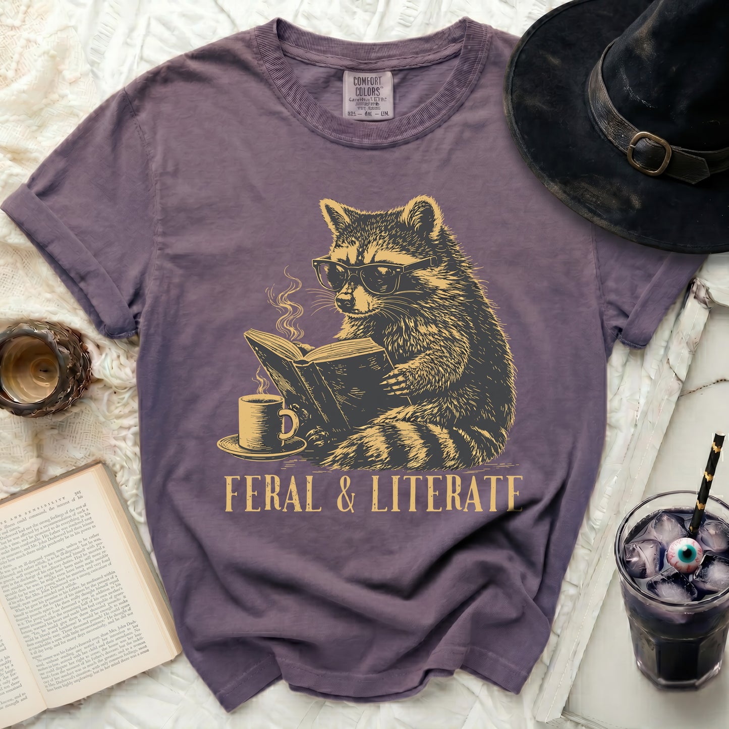 T-shirt with raccoon reading a book and text "FERAL & LITERATE".